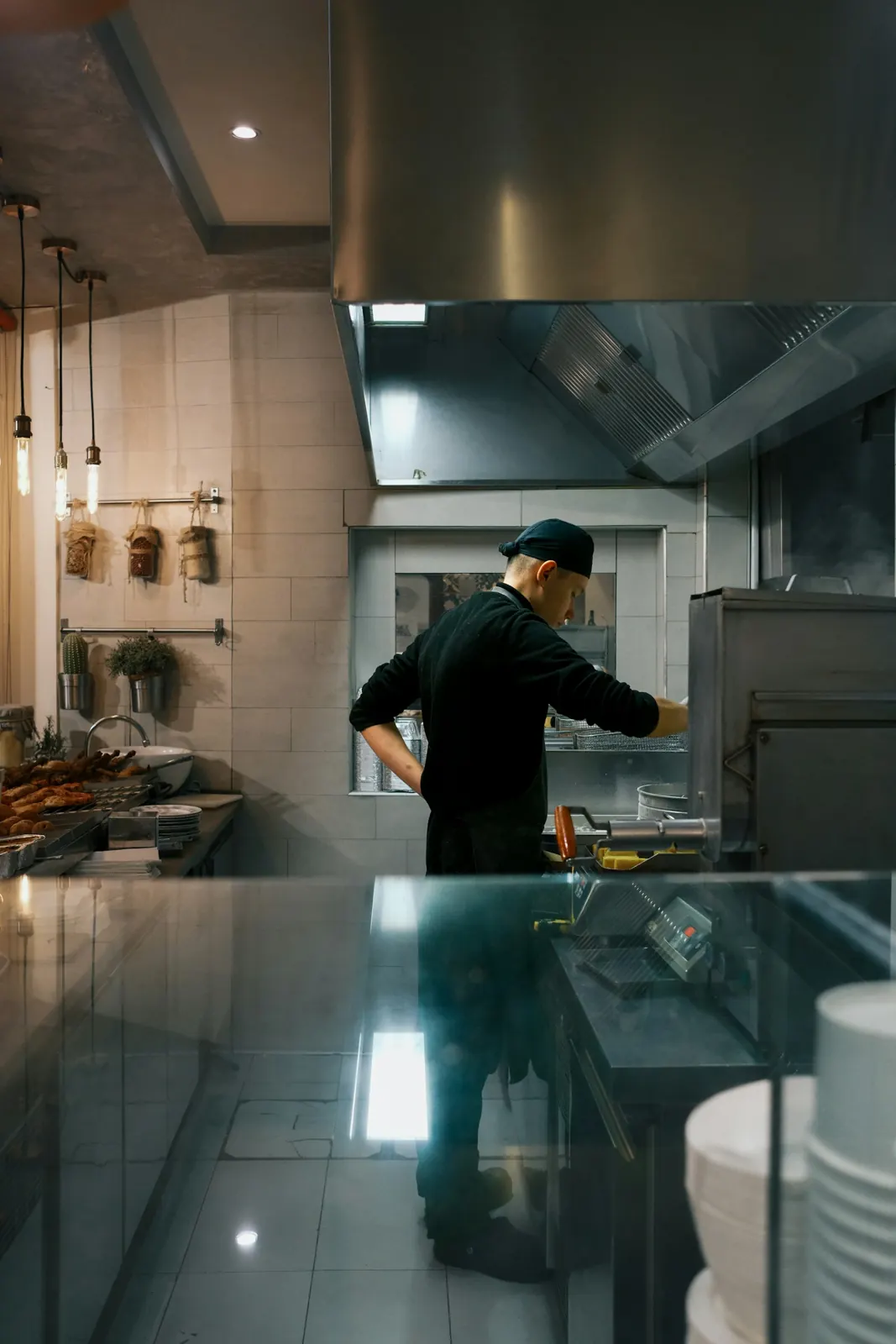 Kok in een zwart jasje aan het werk bij de grill in een restaurantkeuken